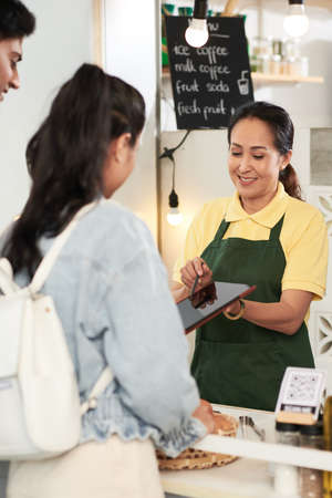Smiling street food cart vendor showing menu on tablet computer to customersの写真素材