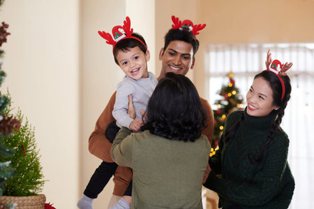 Parents giving excited little son to happy grandmother who came for Christmas vacations