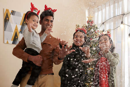Happy family throwing artificial snow at home when celebrating Christmasの写真素材