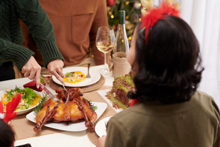 Woman cutting grilled chicken at family dinner for guests