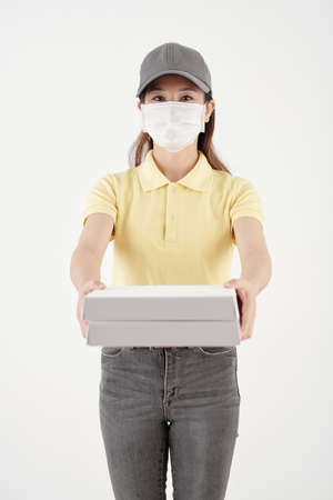 Portrait of courier in protective mask holding boxes of pizzaの写真素材