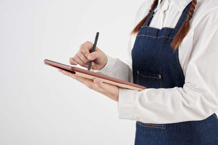 Cropped image of waitress in denim apron checking menu on tablet computerの写真素材