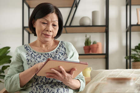 Elderly woman checking banking application online or playing game on tablet computerの写真素材