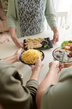 Elderly women putting tasty homemade dishes on table, home party conceptの写真素材