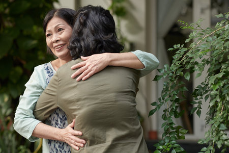 Excited aged woman happy to meet her best friend, they are hugging outdoorsの写真素材