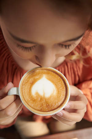 Woman enjoying cup of latte in ther morning, view from the topの写真素材