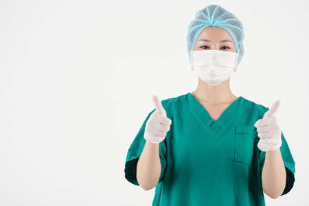 Portrait of happy nurse in protective mask showing thumbs-up with both handsの写真素材