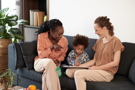 Smiling mothers looking at their talented kid drawing picture
