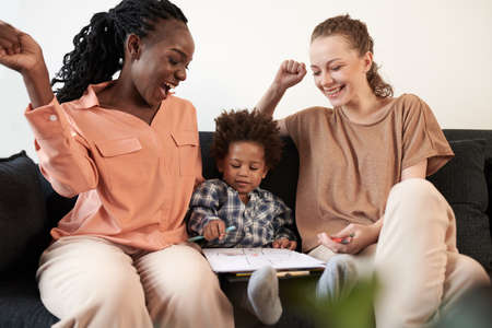 Excited young mothers admiring picture drawn by their talented sonの写真素材