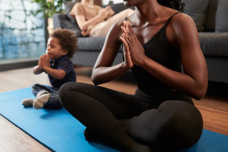 Mother and little son sitting on yoga mat and meditating in lotus positionの写真素材