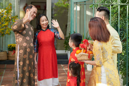 Happy grandparents greeting their children and grandchildren who came for Lunar New Year celebration at house entranceの写真素材