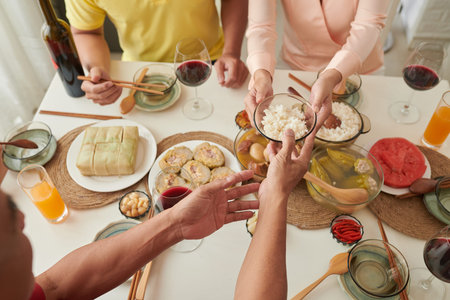 People passing plate over table with traditional Vietnamese Lunar New Year celebration foodの写真素材