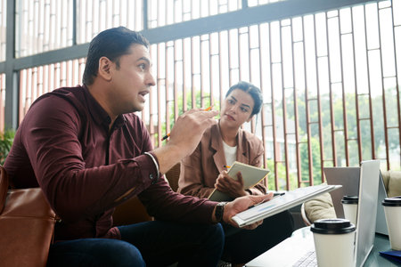 Emotional entrepreneur explaining his idea at meeting with colleaguesの写真素材