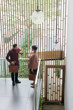 Business colleagues standing on balcony in office building and discussing current workの写真素材