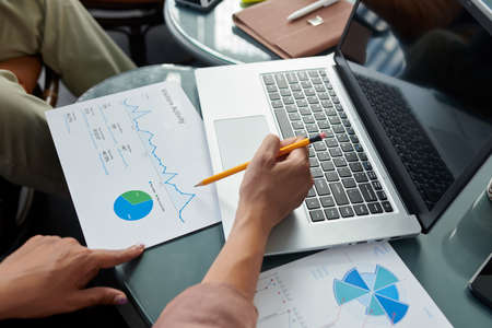 Hands of female entrepreneur discussing chart illustrating website visitors activity with colleague at meetingの写真素材