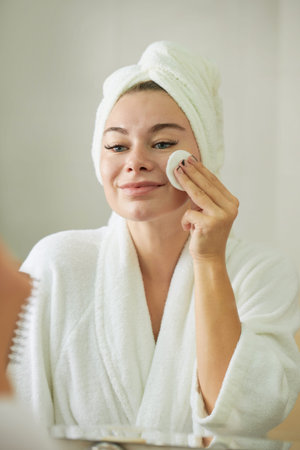 Smiling young woman enjoying beauty morning routine after showerの写真素材