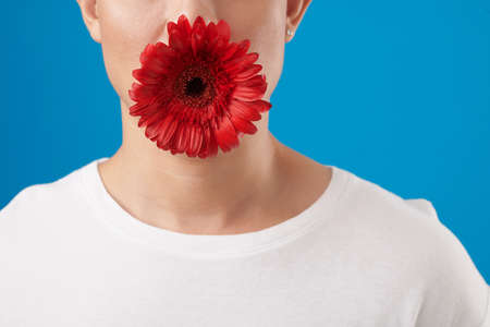 Cropped image of man in white tshirt holding red flower in mouthの写真素材