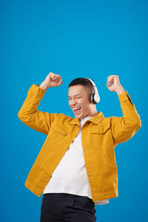Studio portrait of happy excited young man listening to his favorite song again and againの写真素材