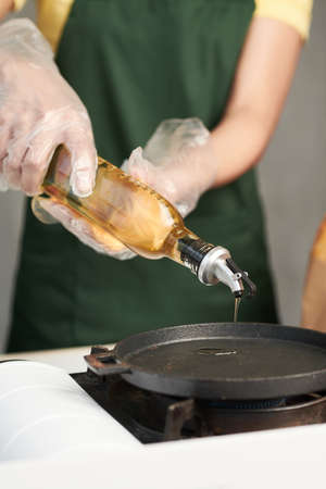 Food cart vendor pouring vegetable oil on pan to cook dish for customerの写真素材