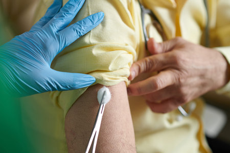 Nurse putting cotton ball on site of injection after injecting vaccine against new stamp of...