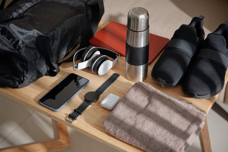Thermos, sneakers, towel and various gadgets next to gym bag