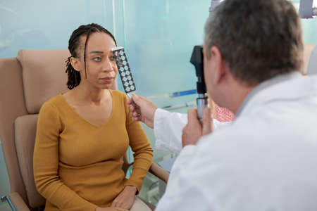 Doctor using pocket ophthalmoscope when examining eyesight of patientの写真素材