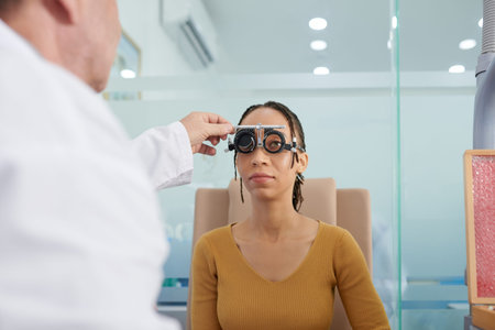 Doctor covering eyes of patient wearing trial frames and asking to read letters on test chart