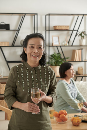 Positive elderly woman with glass of champagne attending house partyの写真素材