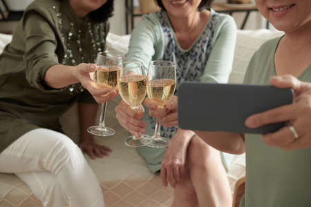 Senior friends taking selfie of them clinking glasses of champagneの写真素材
