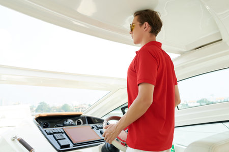 Young man navigating his new luxurious sail boat or yacht floating in sea