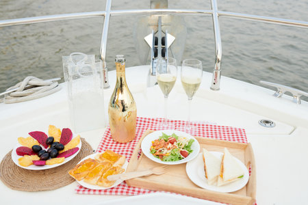 Cold champagne, fresh fruits and delicious snacks served for romantic dinner on yacht bowの写真素材