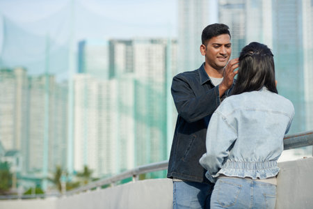 Smiling man looking at girlfriend with love and tenderness and removing hair from her face