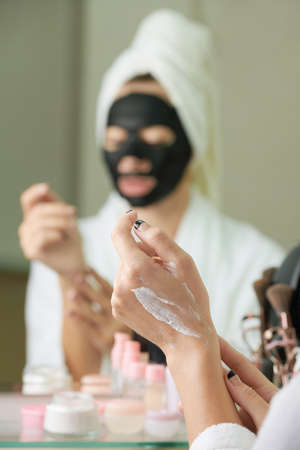 Young woman applying moisturizing body lotion after taking evening showerの写真素材