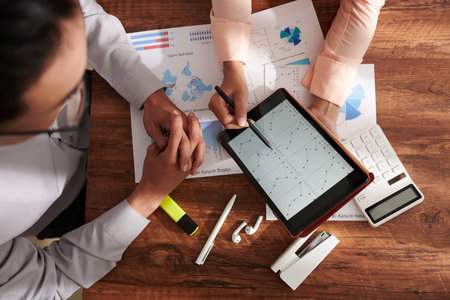 Hands of business people working on startup project and discussing chart on tablet computer