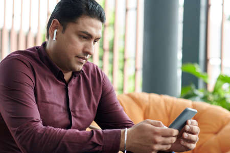 Serious entrepreneur wearing earbuds when making video call to colleague working in office in another countryの写真素材