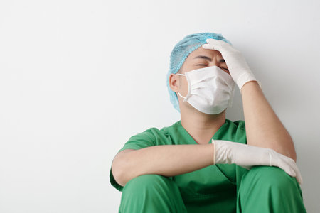 Stressed desperate surgeon in medical mask suffering after loosing patientの写真素材