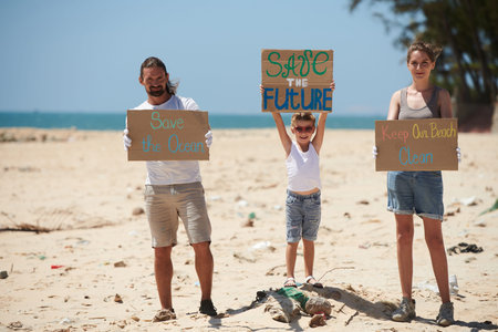Family of activists protesting on dirty beach with placards asking to keep the beach clean