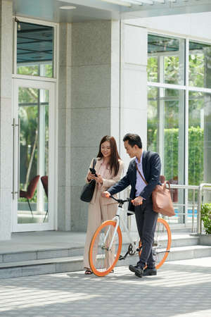 Asian business couple walking down street and discussing new mobile applicationの写真素材