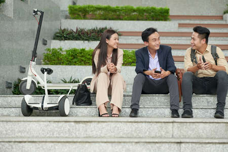 Team of positive staruppers sitting on steps outdoors and discussing new project they are launcing tomorrowの写真素材