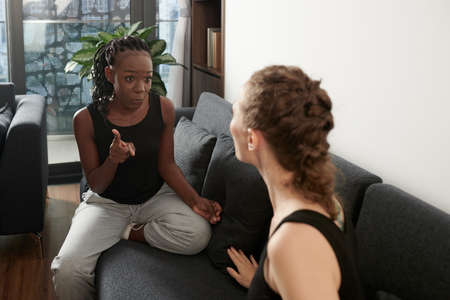Emotional young Black woman proving her point in conversation with girlfriendの写真素材