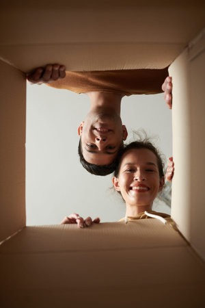 Smiling young man and woman looking inside delivered box with orderの写真素材