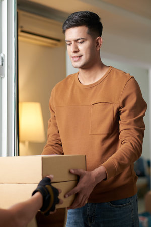 Positive young man receiving boxes delivered by courier