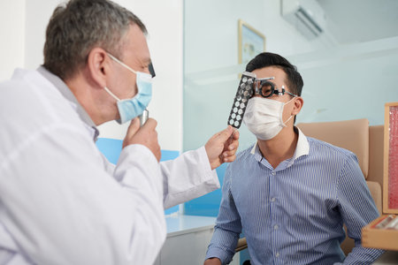 Optometrist holding retinoscopy rack when checking vision of patient in clinicの写真素材