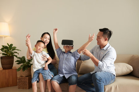 Excited family supporting happy boy winning in virtual reality gameの写真素材