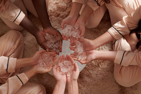 Group of girls holding handffuls of ice cubes over plate, melting glaciers and climate change...