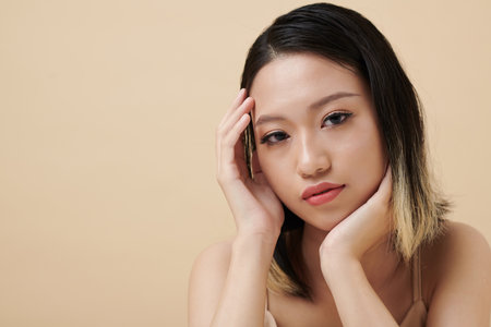 Young woman with neutral face expression thinking at looking at cameraの写真素材