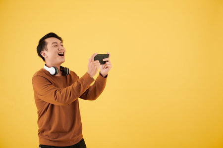 Happy young man winning video game he is playing on smartphone
