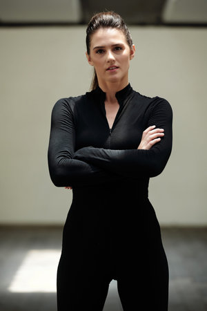 Portrait of confident fit young woman in stretchy sportswear crossing arms and looking at camera