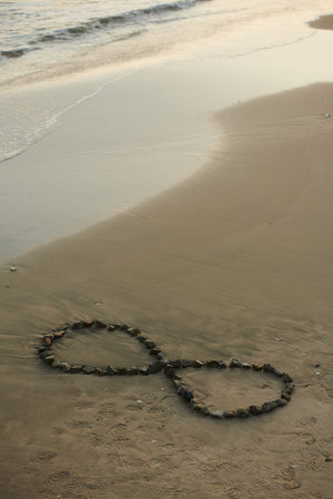 Infinity sign made with small stones on sandy beach