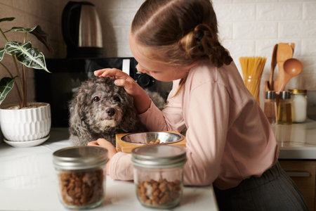 Girl patting dog on head after feeding her with dry food